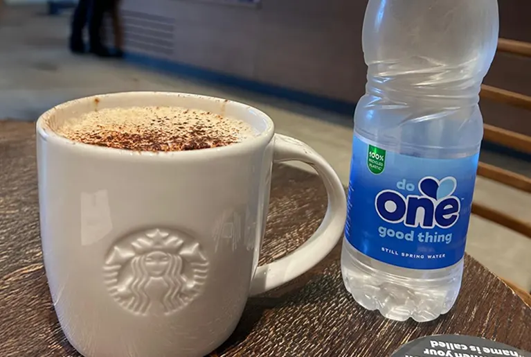 Starbucks cup of coffee and a bottle of One Water